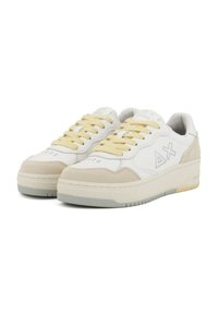 Sneakers bianchi e beige realizzati in pelle e suede, con lacci gialli, perforazioni e una suola in gomma strutturata con dettagli grigi.