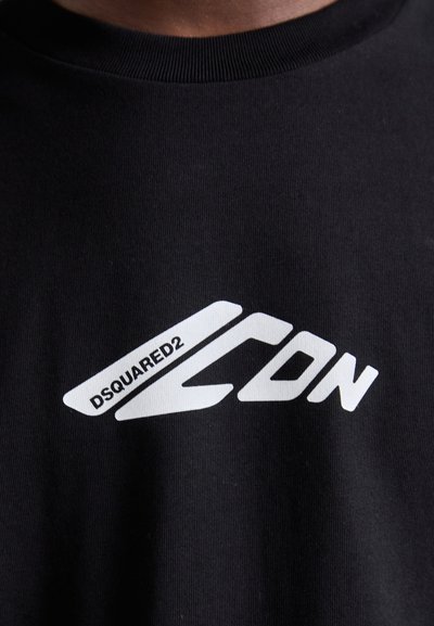 Crna pamučna majica sa bijelim grafičkim logom "DSQUARED2 ICON" s kutnim dizajnerskim elementima na prednjem dijelu. Okrugli ovratnik, kratki rukavi.