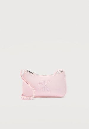 Malá pastelovo ružová kabelka cez rameno so strieborným zipsom a vyrazeným logom "cK" na prednej strane, nastaviteľný popruh stočený vedľa nej.