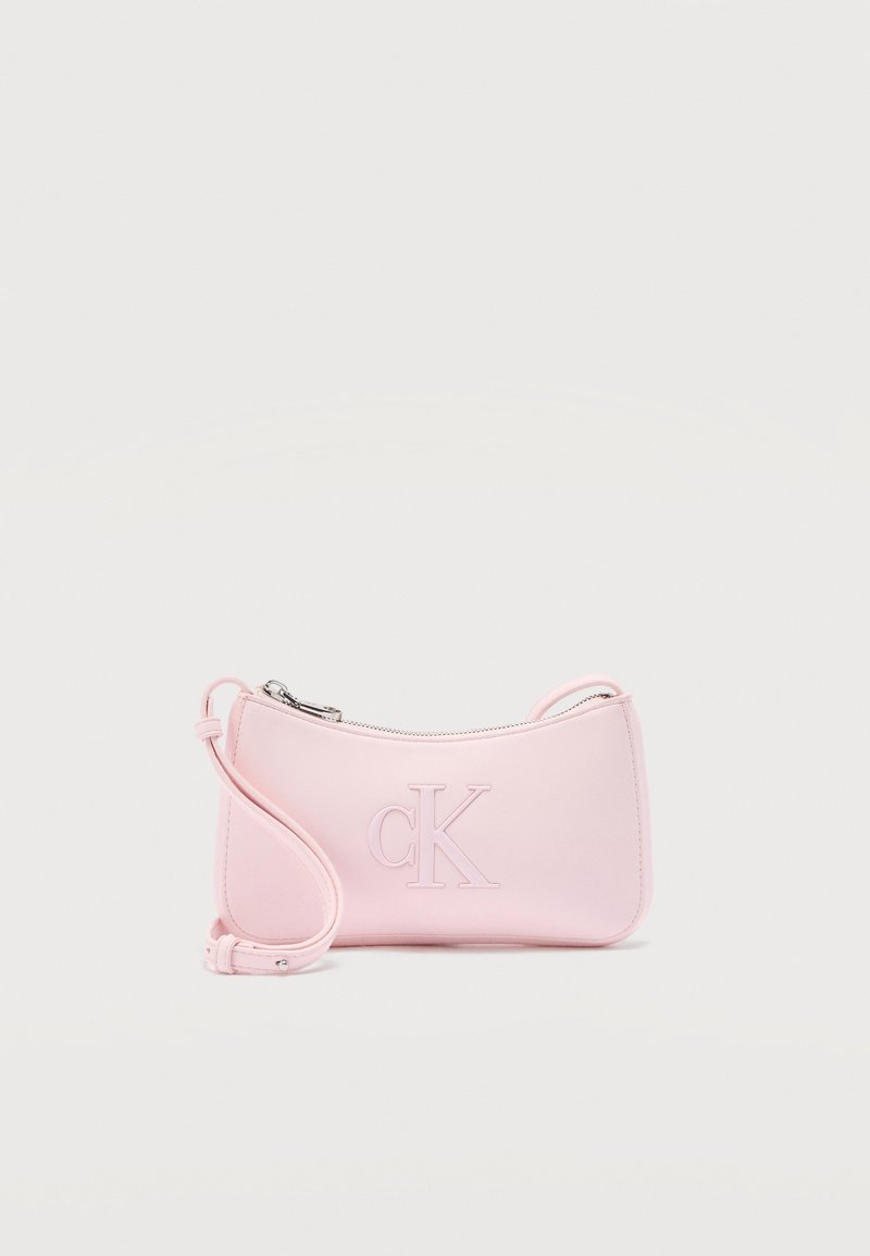 Μικρή παστέλ ροζ τσάντα ώμου με ασημί φερμουάρ και χαραγμένο λογότυπο "cK" στο μπροστινό μέρος, ρυθμιζόμενο λουρί τυλιγμένο δίπλα της.