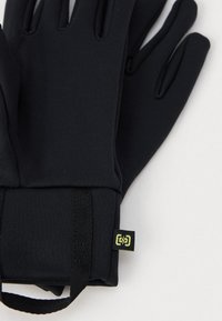 Guantes negros hechos de una tela elástica con una textura suave, con espacios individuales para los dedos y una pequeña etiqueta de logo verde en el puño.