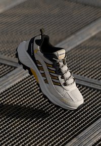 Sportovní tenisky Merrell s šedou síťovinou, černými akcenty, žlutými detaily, polstrovanou podrážkou a bezpečným šněrovacím designem.