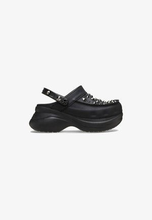 Black clogs with a rounded toe, studded accents on the upper, a back strap, and a chunky sole. Smooth texture, minimalist design.