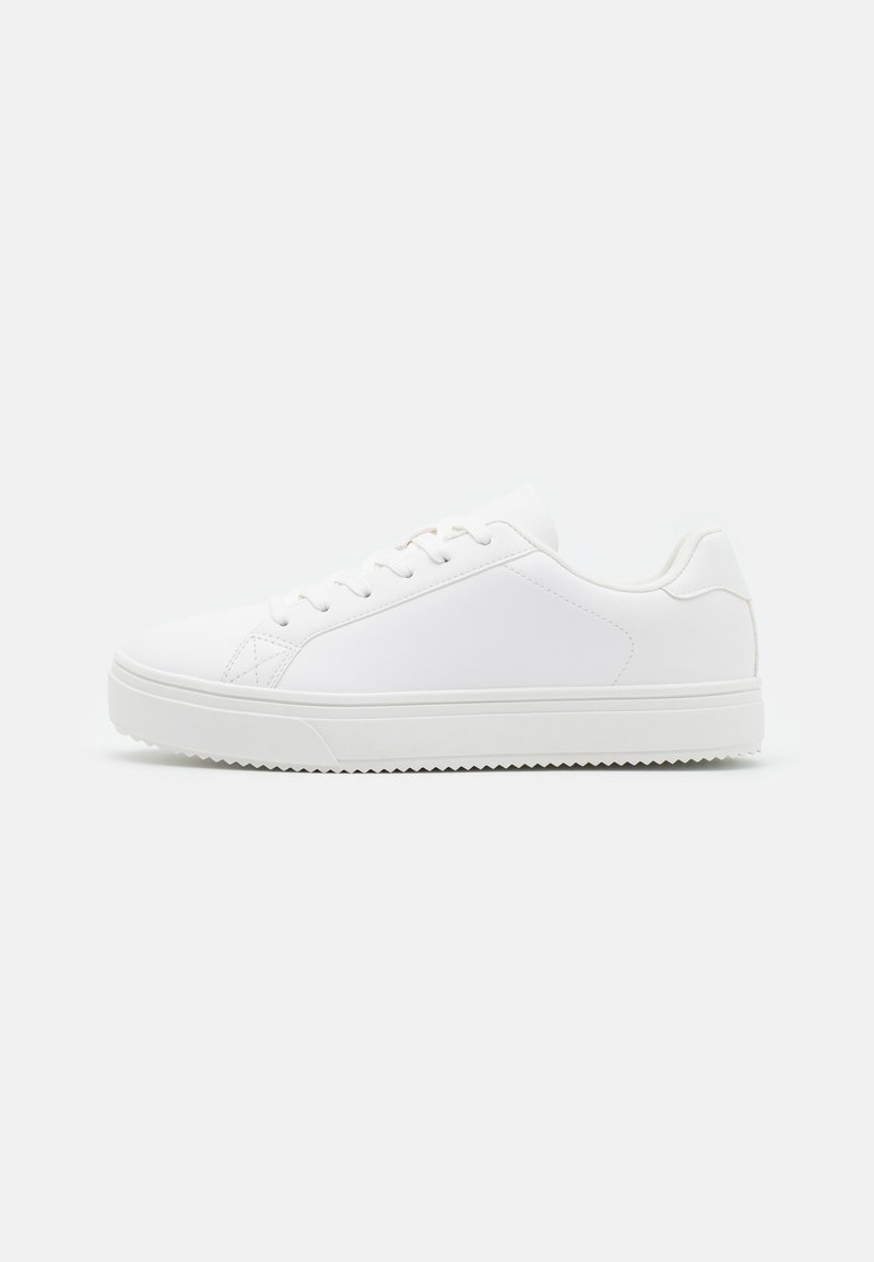 Zapatilla blanca con parte superior sintética lisa, perfil bajo, puntera redondeada, cinco agujeros para cordones y suela de goma texturizada.
