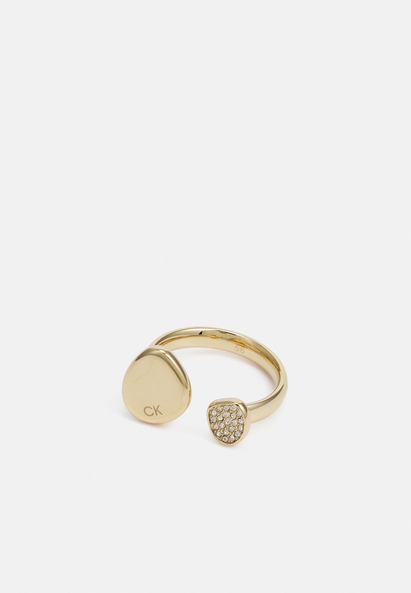 Anello bicolore dorato con un'estremità liscia e arrotondata caratterizzata da un'incisione "CK", e l'altra estremità decorata con cristalli tondi e trasparenti.