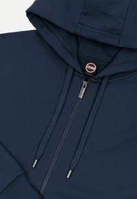 Μπλε ναυτικό hoodie με φερμουάρ, κορδόνια και εμφανές εσωτερικό ταμπελάκι με την επωνυμία Colmar Originals στο πέτο.