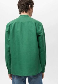 Green long-sleeve shirt made from cotton, featuring a back yoke, two-button cuffs, and a relaxed fit. Worn with blue jeans.