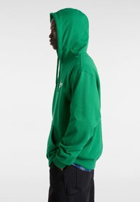 Felpa verde con cappuccio in morbido tessuto. Presenta una tasca frontale a marsupio, cappuccio con cordini e dettaglio del logo sul petto.