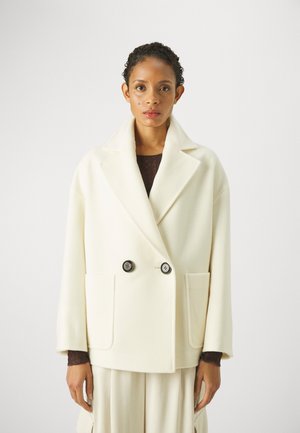 Cappotto doppiopetto color crema in lana con rever a punta, due tasche frontali e bottoni neri. Tessuto morbido e vestibilità rilassata.