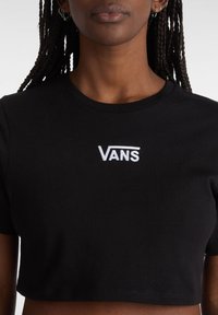 Sort kort T-shirt lavet af bomuld. Har en rund hals og broderet hvidt "VANS" logo på brystet. Glat tekstur, korte ærmer.