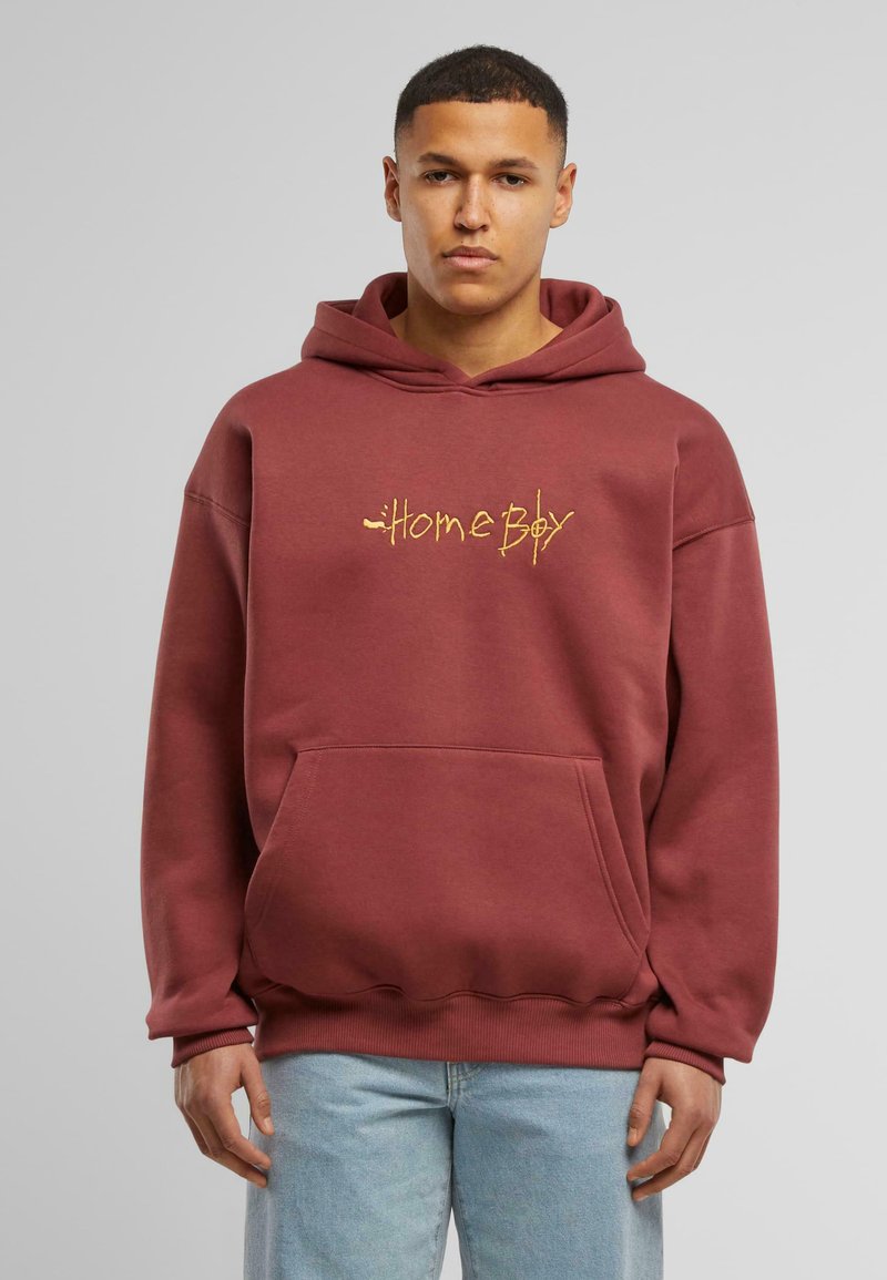 Bordová mikina z jemného materiálu s klokanhým vreckom. Obsahuje žltý nápis "Home Boy" v písmovom štýle. Rybárske manžety a lem.