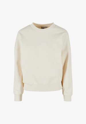 Hanorac crem cu guler dintr-o țesătură cu nervuri, mâneci lungi și o croială lejeră. Are broderie subtilă cu semnătura în alb pe partea din față.