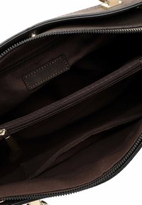 Brown interior of a handbag with dual compartments, a zippered pocket, gold hardware, and a smooth texture. Tag visible inside.
