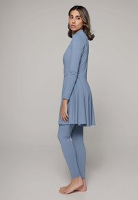 Lichtblauwe bescheiden zwemset met lange mouwen en een uitlopende tuniek over aansluitende leggings. Gemaakt van stretchy, gladde stof.