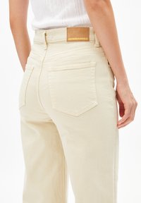 Beige jeans met een hoge taille en rechte pijpen, met achterzakken en een leren label met de naam ARMEDANGELS. Zachte, gestructureerde stof.