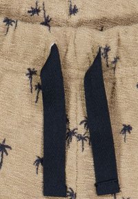 Béžové froté šortky s tmavě modrými šňůrkami, s dekorativním vzorem malých palmových stromů v námořnické modři po celém materiálu.