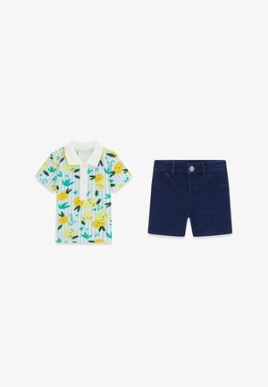 Chemise à manches courtes avec col et imprimé citron et feuilles à côté d'un short bleu marine à boutons sur le devant, présenté sur fond blanc.