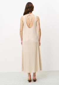 Beige ärmelloses Maxikleid mit tiefem Rücken und Bindegürtel, das eine gerippte Textur aufweist. Der Saum ist gerade und reicht unter die Knöchel.