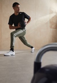 adidas Sportswear ESSENTIALS TAPERED CUFF 3-STRIPES  - Treniņtērpa apakšdaļas - olive strata