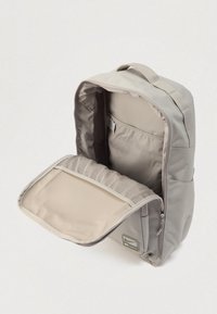 Γκρι σακίδιο με μαλακή εξωτερική επιφάνεια, κεντρικό διαμέρισμα με φερμουάρ και δίχτυ τσέπη στο εσωτερικό. Διαθέτει λαβή στην κορυφή και διακριτική σήμανση.