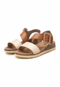 Sandalias marrones y beige con una amplia correa superior, hebilla ajustable, planta suave y una suela baja y texturada.