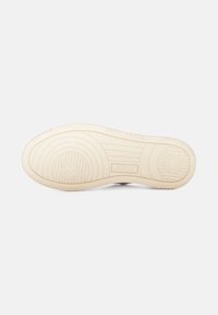 Suola della scarpa in gomma beige con motivi circolari e lineari. Presenta un logo "AUTRY" e un bordo spesso e testurizzato per garantire aderenza.