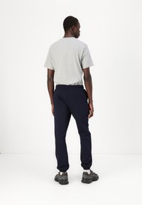 Grijze t-shirt met korte mouwen en marineblauwe joggingbroek met elastische boorden, gezien van achteren. De outfit heeft een relaxte pasvorm en een zachte stof.