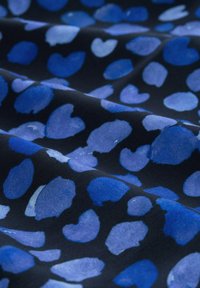 Tessuto blu con motivi a forma di cuore su uno sfondo scuro. La texture è liscia e presenta diverse tonalità di blu.