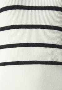 Pull en maille avec une texture côtelée présentant des rayures noires horizontales sur un fond blanc. Tissu doux et design décontracté.