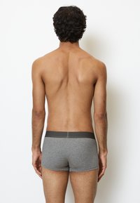 Grå boxershorts med en mörkgrå midja, figursydd design och slät textur. Vyn visar produkten bakifrån mot en enkel bakgrund.
