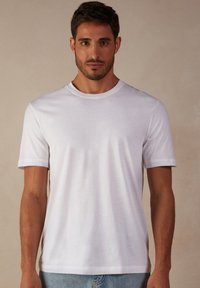 T-shirt en coton blanc à manches courtes avec un col rond ; texture lisse ; coupe classique. Aucun motif ni accent visible.