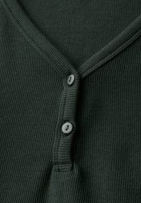 Maglietta henley a coste verde scuro con scollo a V, arricchita da tre bottoni grigi lungo la pattina e da un tessuto testurizzato.