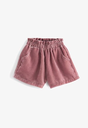 Różowe aksamitne szorty z elastycznym paskiem w talii i bocznymi kieszeniami, połączone z wzorzystymi różowymi rajstopami i pasującymi różowymi botkami za kostkę.