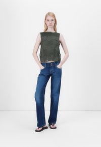 Grønn heklebluse med rund hals, kombinert med blå rette jeans og svarte flip-flops. Enkelt, casual antrekk.