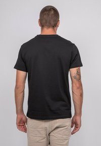 T-shirt noir à manches courtes avec un design classique, en coton. Il présente un col rond et une texture uni, sans logos ni graphiques visibles.