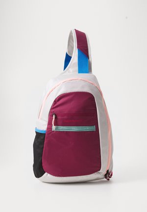 Sling backpack in purple, grey, and black nylon with a front zip pocket, blue strap, and pink accents; features a smooth, textured surface.