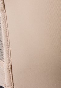 Beige fabric with a ribbed texture and a mesh panel. Features delicate stitching along the edges. Smooth and stretchy material.