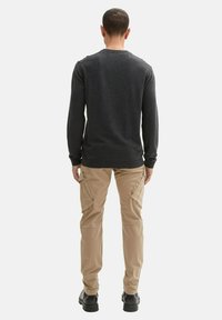 Dunkelgrauer langärmeliger Pullover mit Rundhalsausschnitt, kombiniert mit hellbeigen Cargo-Hosen mit Seitentaschen und schmaler Passform.