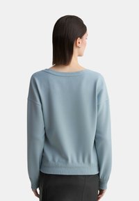 Maglione a collo ampio in blu chiaro, con polsini e orlo a costine. Texture morbida, vestibilità casual e spalle scese.