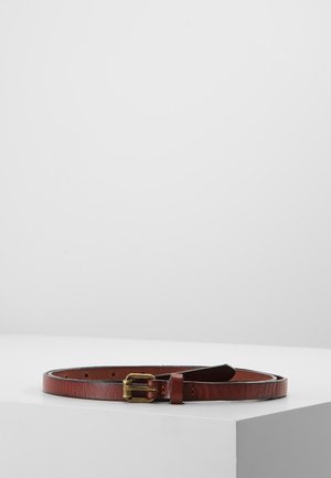 Brązowy skórzany pasek z małą złocistą klamrą, zwinięty płasko na białej powierzchni na tle jednolitego szarego tła.