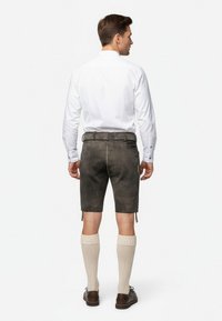 Mörkgrå lädershorts för män med en slät yta, knälånga, tillsammans med krämfärgade knästrumpor, bärs med en vit långärmad skjorta.