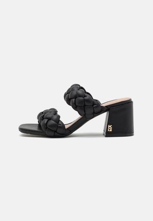 Sort højhælet sandal med to brede flettede remme og en blokhæl med lille gulddetalje med logo.