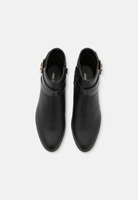 Botas de cuero negro hasta el tobillo con punta afilada, que cuentan con una banda texturada con relieve de cocodrilo y un acento de hebilla lateral. Acabado suave y pulido.