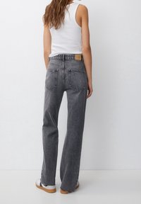 Jean en denim gris taille haute à coupe décontractée, avec un patch en cuir à l'arrière, un design à cinq poches et un ourlet effiloché.