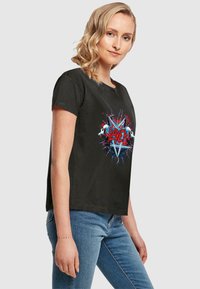 T-shirt nera in cotone con un vivace design grafico che presenta un teschio e un motivo di pentagramma, maniche corte e vestibilità rilassata.