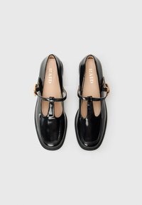 Pair of black patent leather Mary Jane shoes with buckle straps and square toes, laid flat on a white background.