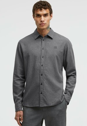 Gray button-up shirt with a collar and long sleeves, featuring a subtle texture, black buttons, and a small embroidered logo on the chest.