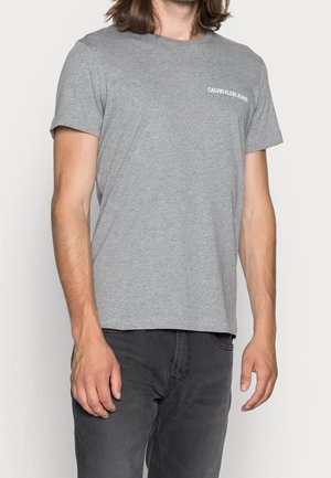 Grijze katoenen t-shirt met korte mouwen, ronde halslijn en klein wit "CALVIN KLEIN JEANS" logo op de linkerkant van de borst. Casual pasvorm.