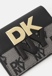 Svart lommebok med en glatt overflate, fremtredende gull "DK"-logo og teksturfelt med preget "NY"-mønster.