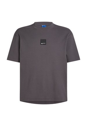 Siva kratka majica s kratkimi rokavi iz teksturirane rebraste tkanine, okrogel izrez in črno kvadratno nalepko na sprednjem delu. Mehka, sproščena kroja.